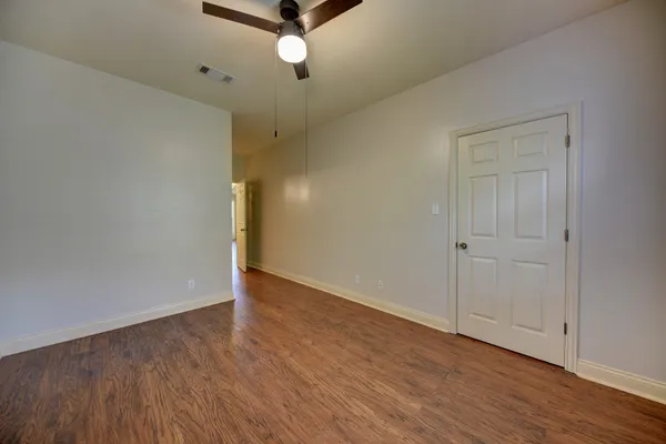 an empty room with wooden floor closet and windows