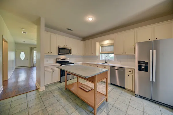 a kitchen with kitchen island granite countertop stainless steel appliances cabinets a sink and a counter top space