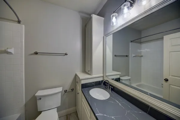 a bathroom with a granite countertop sink toilet a mirror and shower