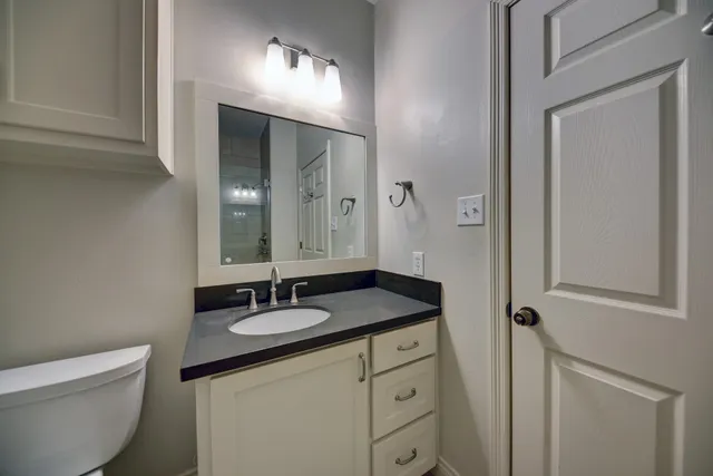 a bathroom with a granite countertop sink a toilet and a mirror