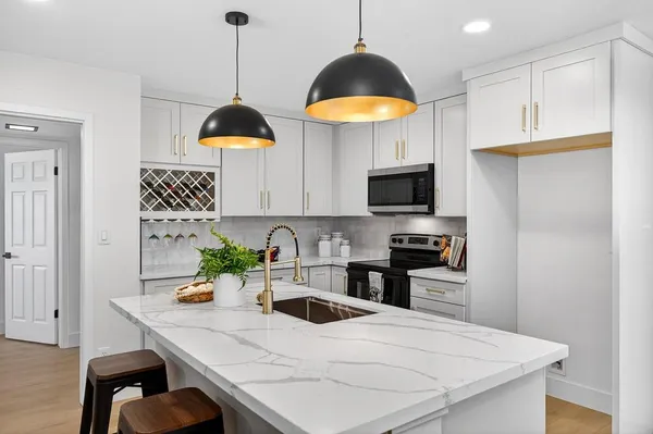 a kitchen with stainless steel appliances granite countertop a sink a stove and a wooden floors