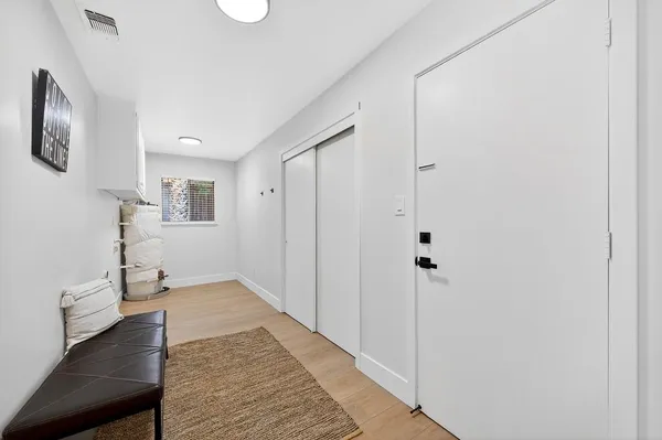 a view of a hallway with wooden floor and a bathroom