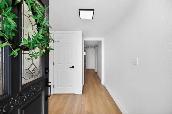 a view of a hallway with wooden floor and a potted plant