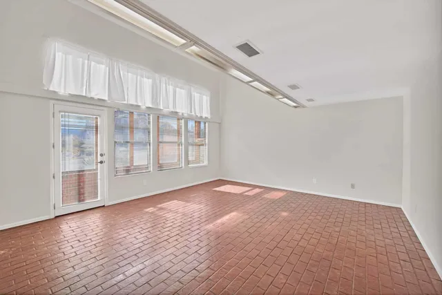 a view of an empty room with wooden floor and windows