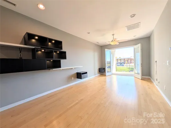 a view of an empty room with window and wooden floor