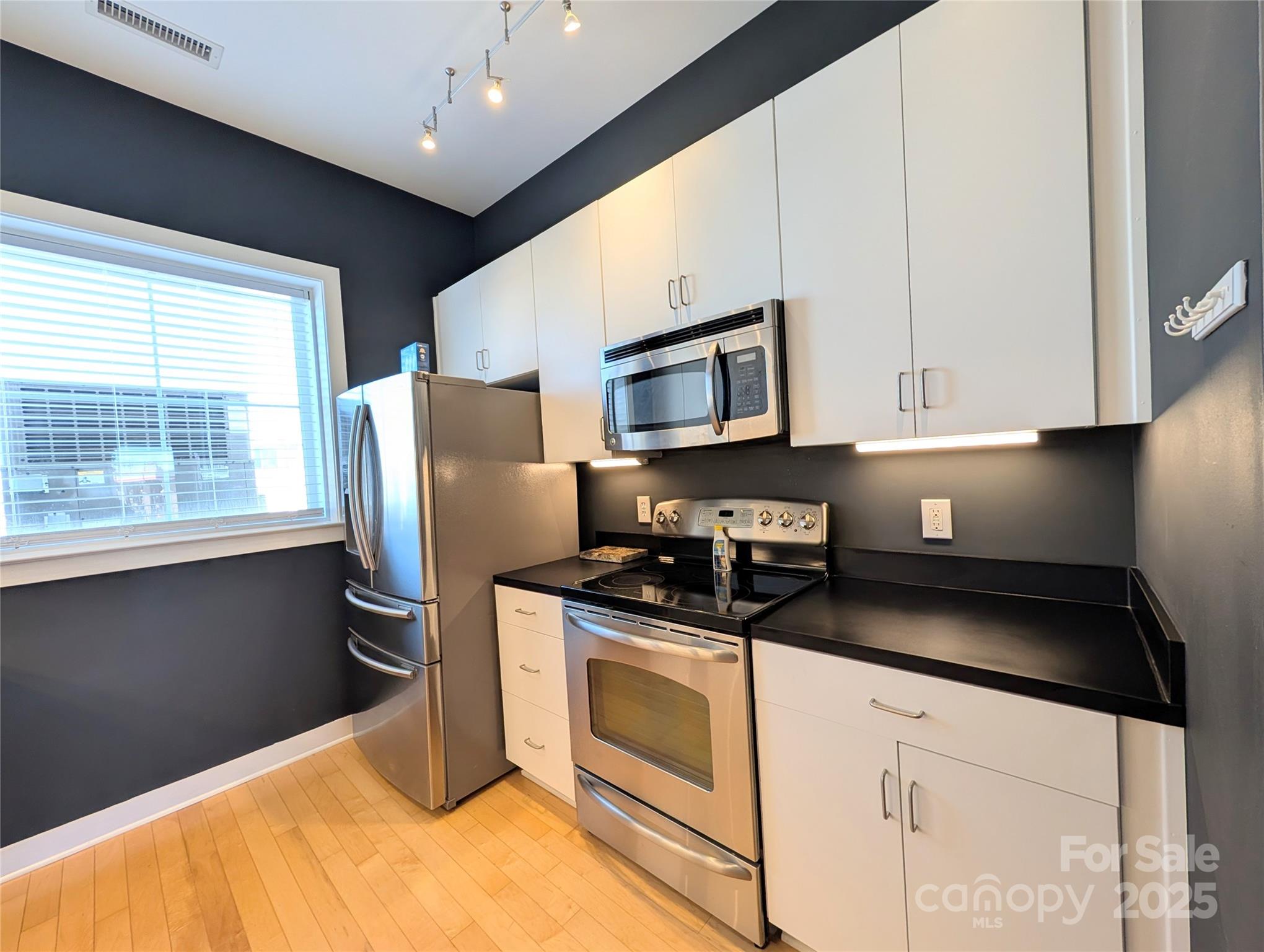 360 Exchange Street Northwest, Unit 206 Concord, NC 28027 - Photo 9 of 28 a kitchen with stainless steel appliances granite countertop a stove a sink and a microwave