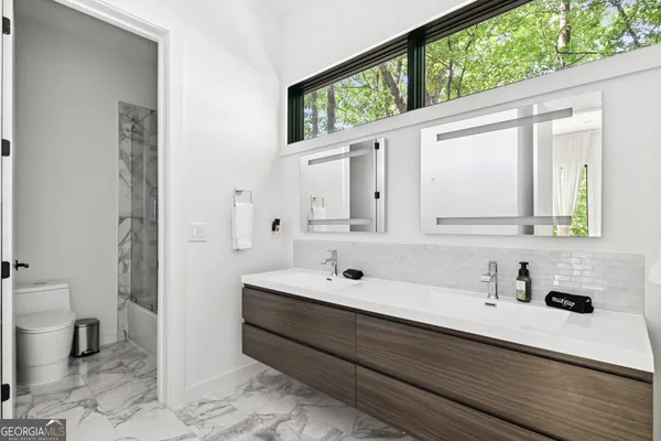 a bathroom with a double vanity sink toilet and a mirror