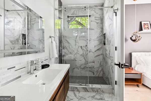 a bathroom with a granite countertop shower a sink and a mirror