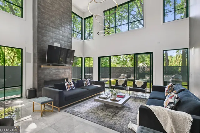 a living room with furniture fireplace and large windows