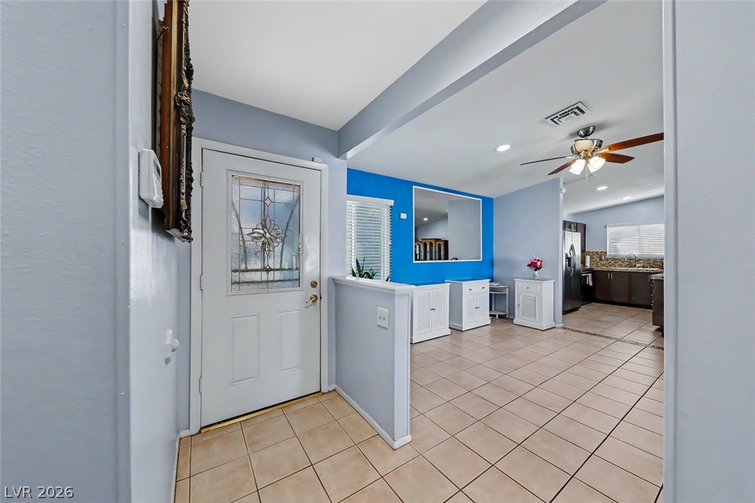 3107 Trueno Road Henderson, NV 89014 - Photo 10 of 37 A welcoming entry features a leaded glass front door, opening into a tiled open-concept living area.