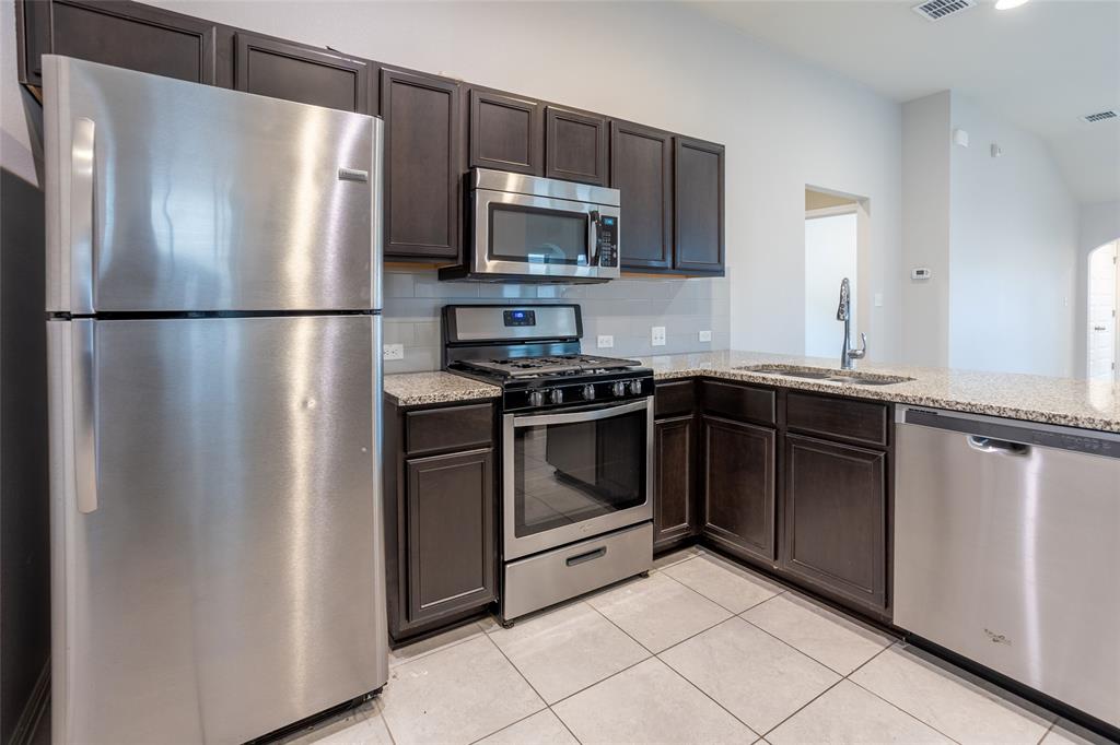 615 Stampede Road San Marcos, TX 78666 - Photo 20 of 26 A well-appointed kitchen features dark wood cabinetry, granite countertops, and modern stainless steel appliances.