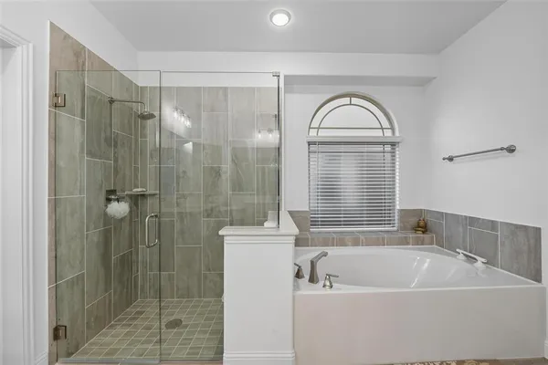 a bathroom with a bathtub a window and a shower