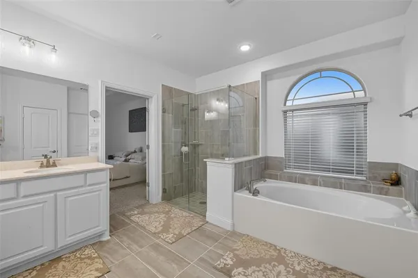 a spacious bathroom with a tub sink shower and mirror