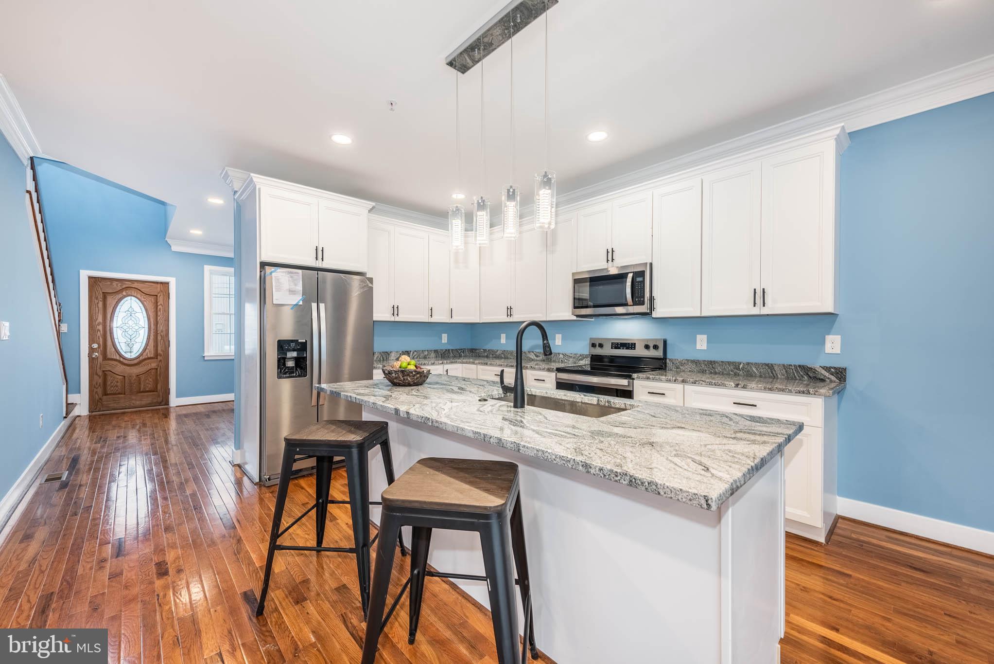 8307 Bletzer Road Baltimore, MD 21222 - Photo 11 of 37 a kitchen with stainless steel appliances granite countertop a stove top oven a refrigerator a sink and a dining table with wooden floor