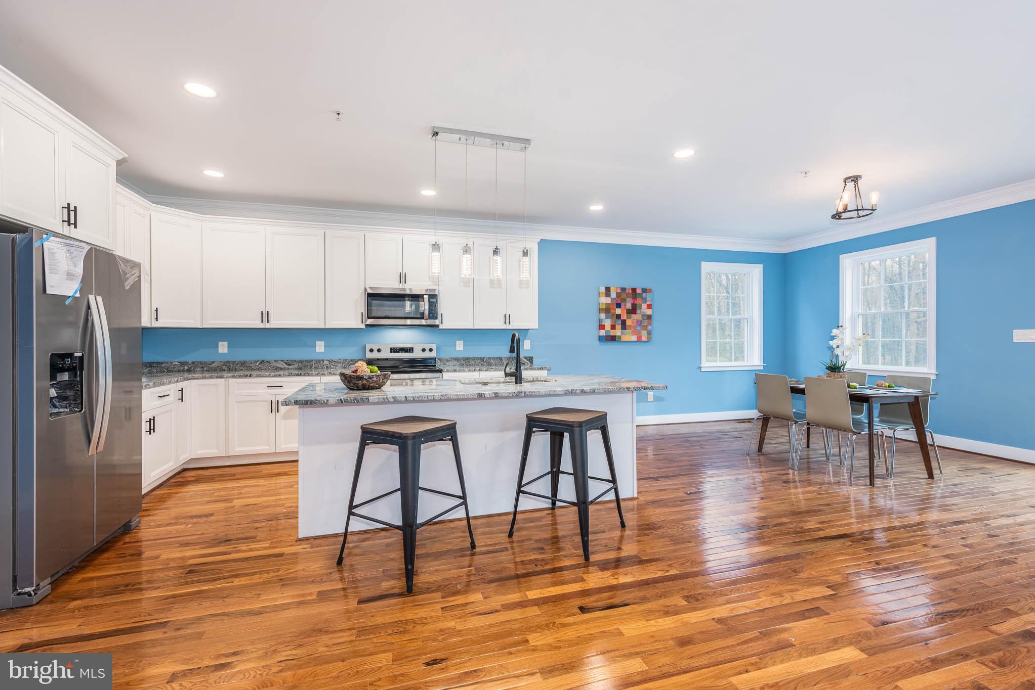 8307 Bletzer Road Baltimore, MD 21222 - Photo 9 of 37 a kitchen with stainless steel appliances granite countertop a refrigerator a stove top oven a dining table and chairs with wooden floor