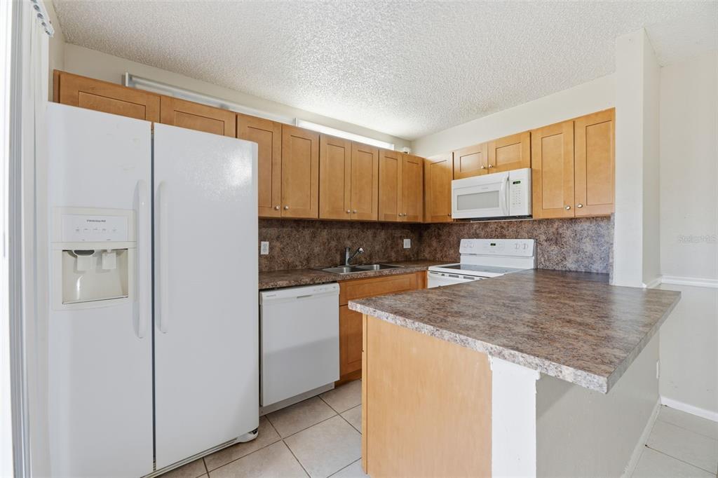 238 Woodland Road Palm Springs, FL 33461 - Photo 10 of 33 a kitchen with stainless steel appliances granite countertop a refrigerator a sink and white cabinets