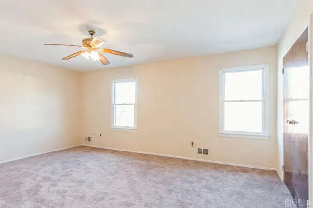 an empty room with windows and fan