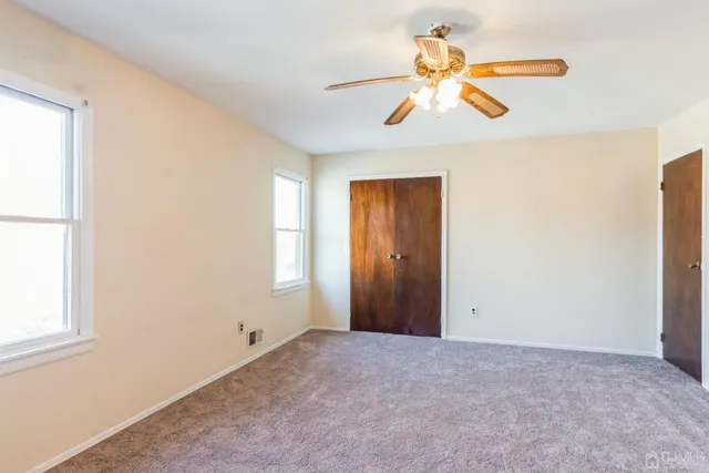an empty room with closet and a chandelier fan