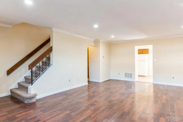 a view of an empty room with wooden floor and stairs