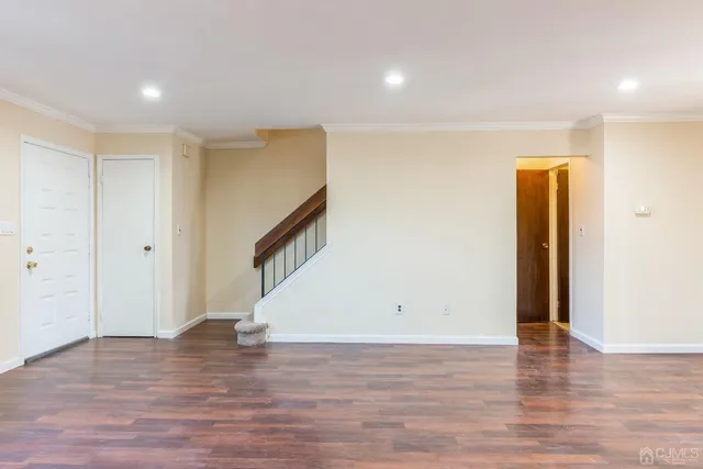 a view of an empty room with wooden floor and stairs
