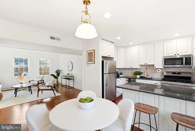 a kitchen with stainless steel appliances granite countertop a dining table and chairs