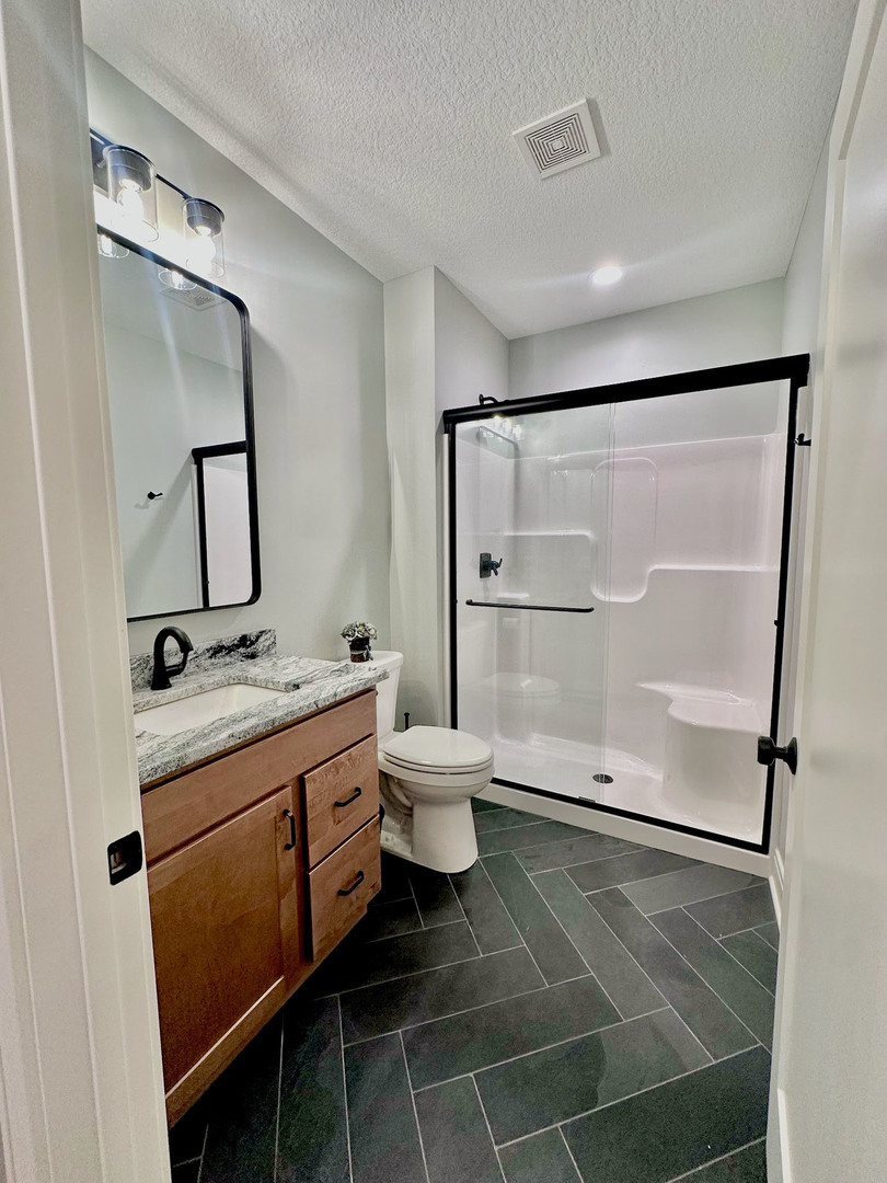 5077 Oak Rdg Court Bettendorf, IA 52722 - Photo 30 of 35 a bathroom with a granite countertop sink toilet a mirror and shower