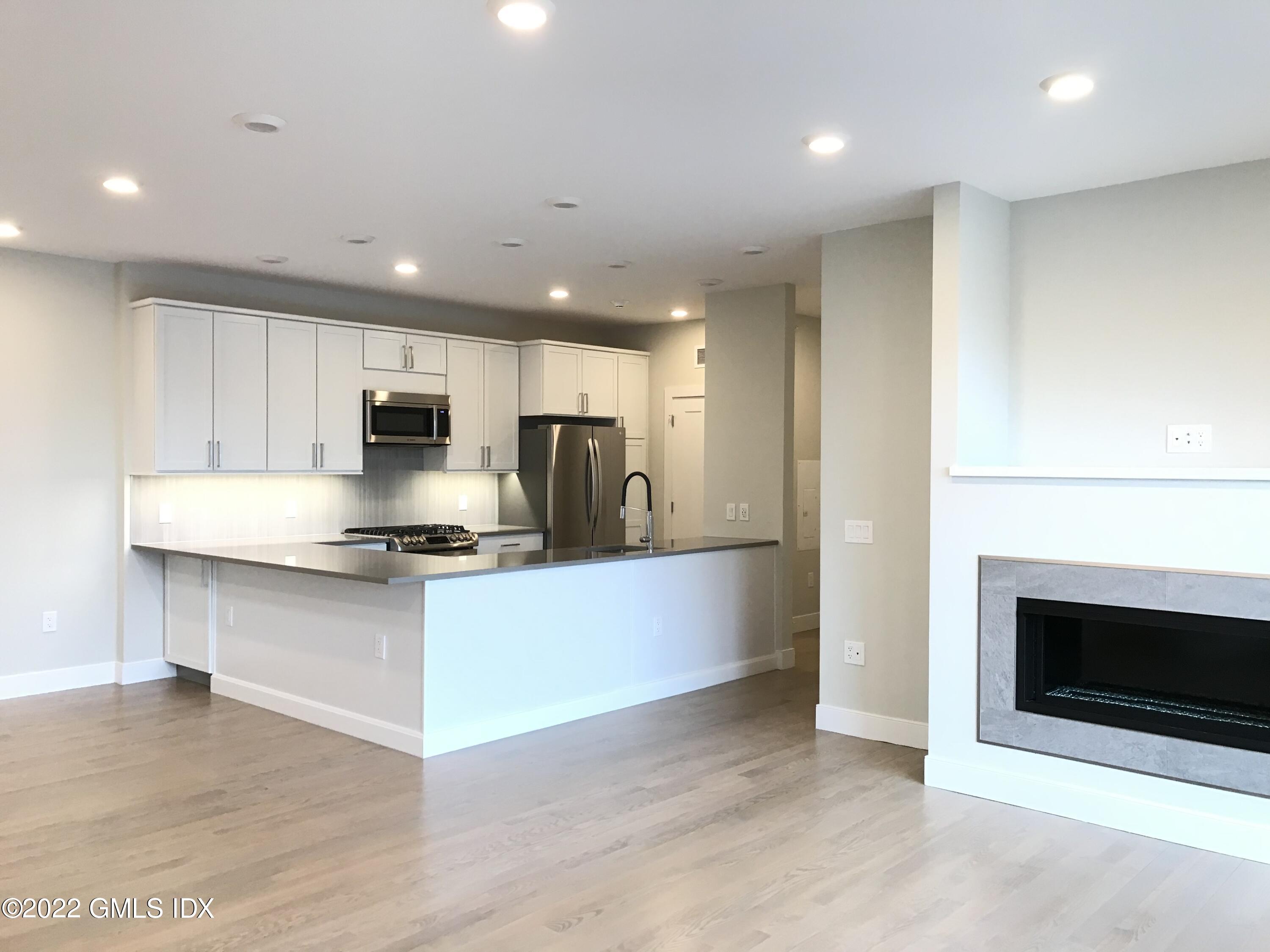 56 Old Field Point Road, Unit 6 Greenwich, CT 06830 - Photo 10 of 28 a large kitchen with stainless steel appliances granite countertop a stove a microwave and a refrigerator