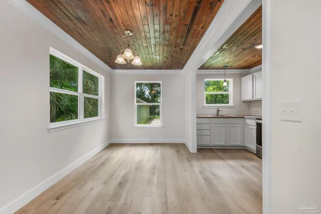 a view of a kitchen and an empty room with a window