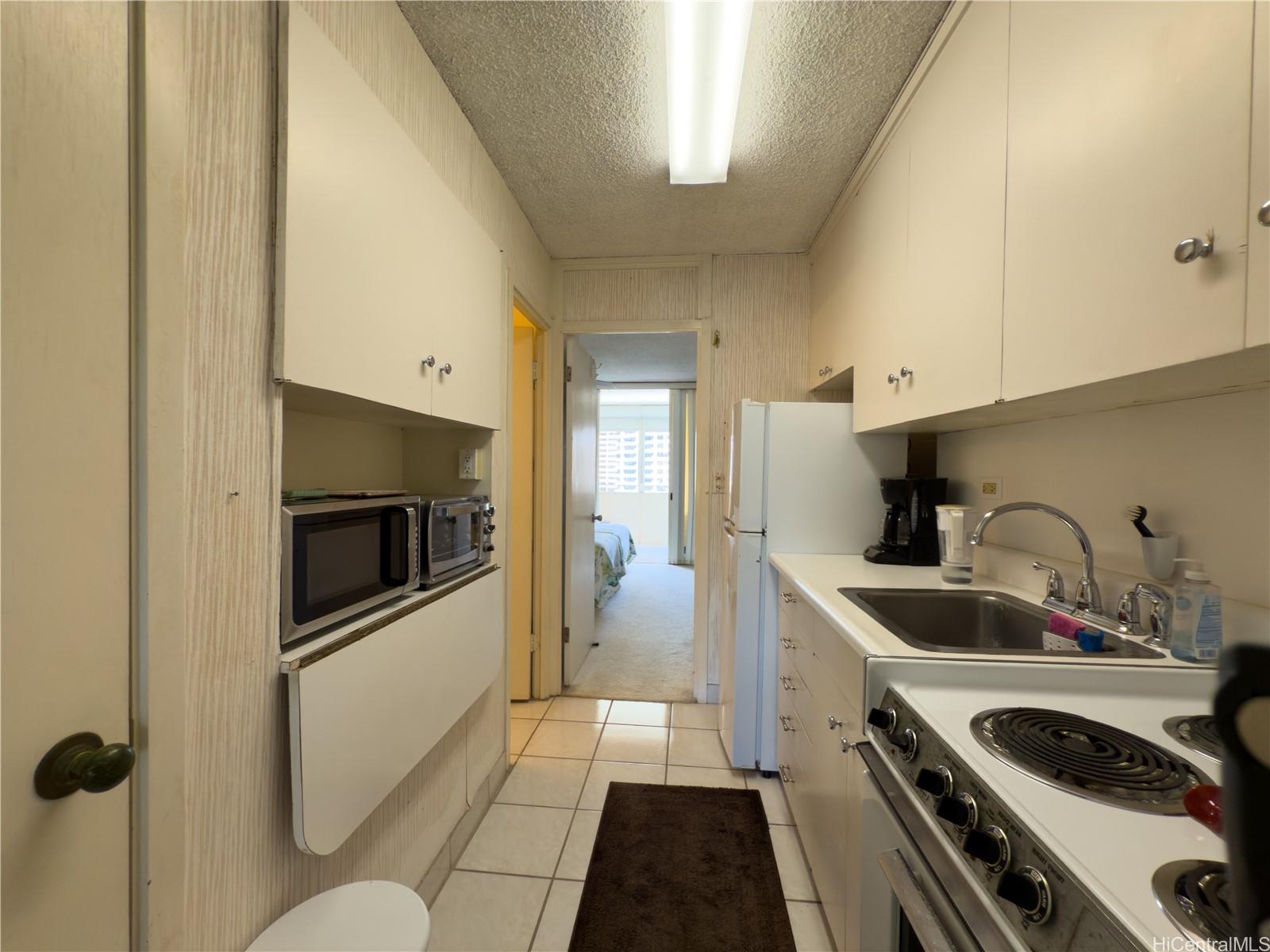 425 Ena Road, Unit 1201B Honolulu, HI 96815 - Photo 9 of 20 a kitchen with a sink and white cabinets