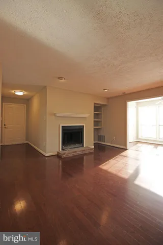 a view of empty room with wooden floor and fireplace