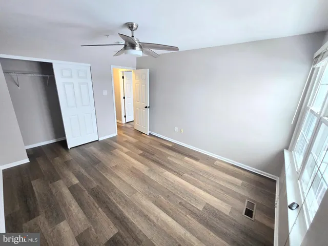 an empty room with wooden floor fan and windows