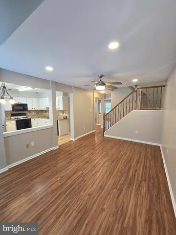 a view of empty room with wooden floor and kitchen view