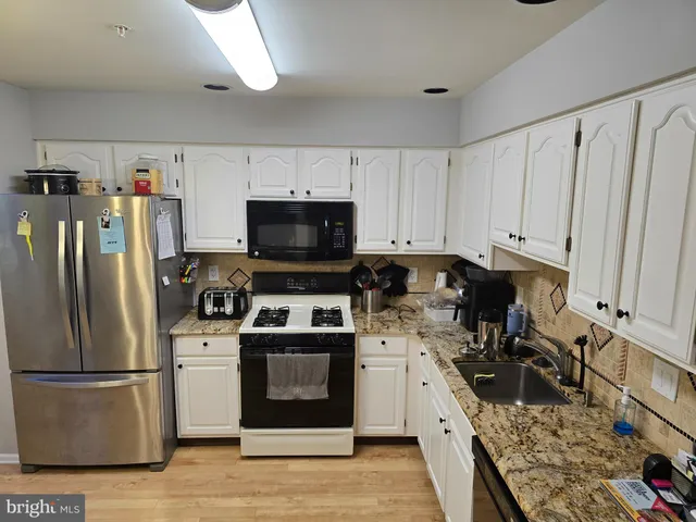 a kitchen with a refrigerator a stove top oven a sink and cabinets
