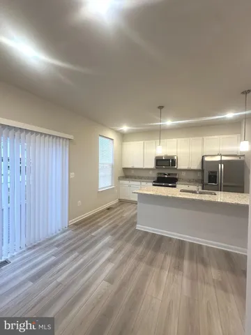 a large kitchen with kitchen island a stove a refrigerator a sink dishwasher with a dining table and chairs with wooden floor