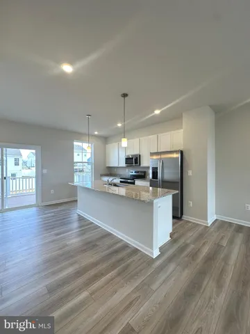 a large kitchen with kitchen island a sink dishwasher a refrigerator and a stove with wooden floor