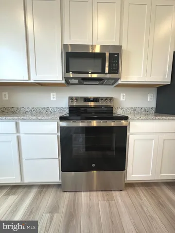 a kitchen with stainless steel appliances granite countertop a stove a microwave a sink and cabinets