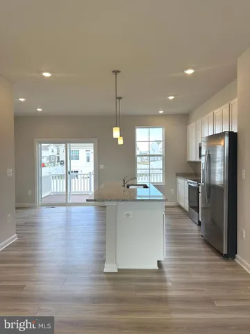 a large kitchen with stainless steel appliances wooden floor and large window