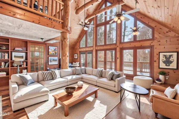an empty room with wooden floor fireplace and windows