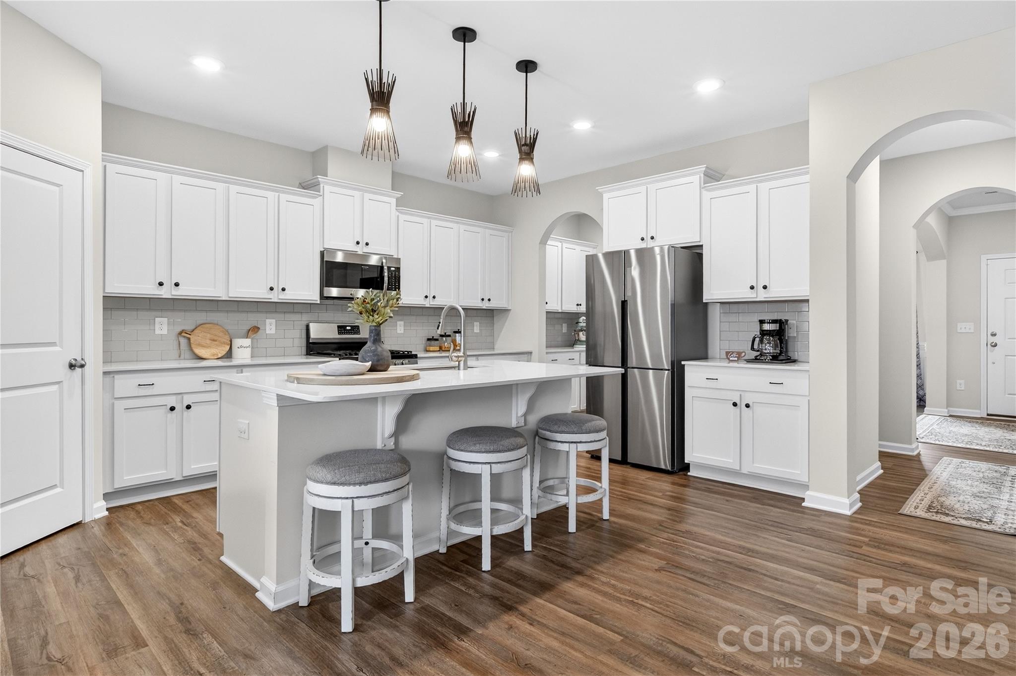 151 Outrigger Lane Troutman, NC 28166 - Photo 15 of 39 a kitchen with stainless steel appliances granite countertop a refrigerator a stove a sink and white cabinets with wooden floor
