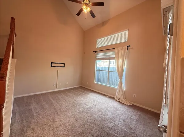 an empty room with a ceiling fan and window