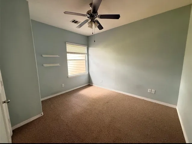 an empty room with a window and a fan