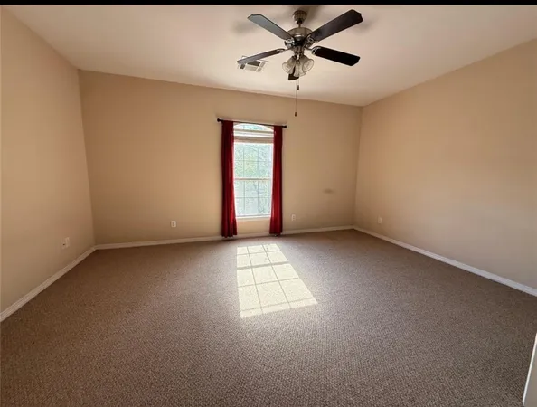 an empty room with windows and fan