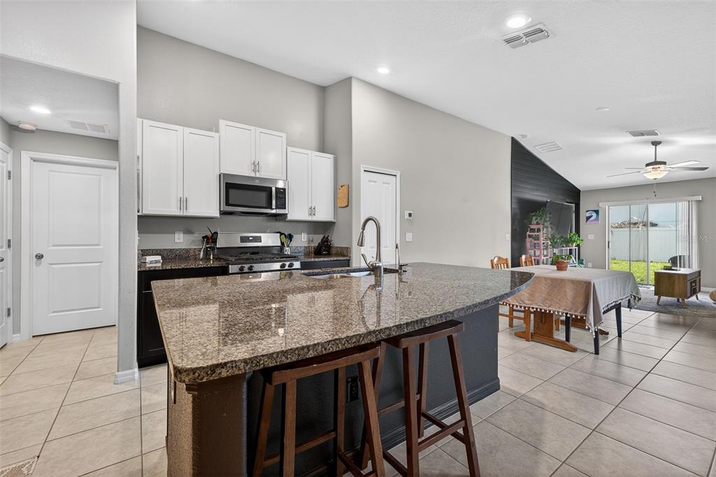 9324 Lemon Drop Loop Sun City Center, FL 33573 - Photo 5 of 32 a kitchen with granite countertop a stove a sink a microwave a dining table and chairs