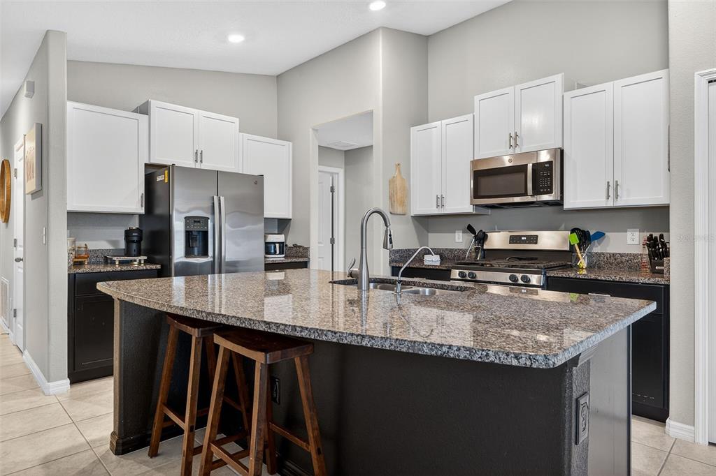 9324 Lemon Drop Loop Sun City Center, FL 33573 - Photo 7 of 32 a kitchen with stainless steel appliances granite countertop a sink a stove a refrigerator a center island and cabinets