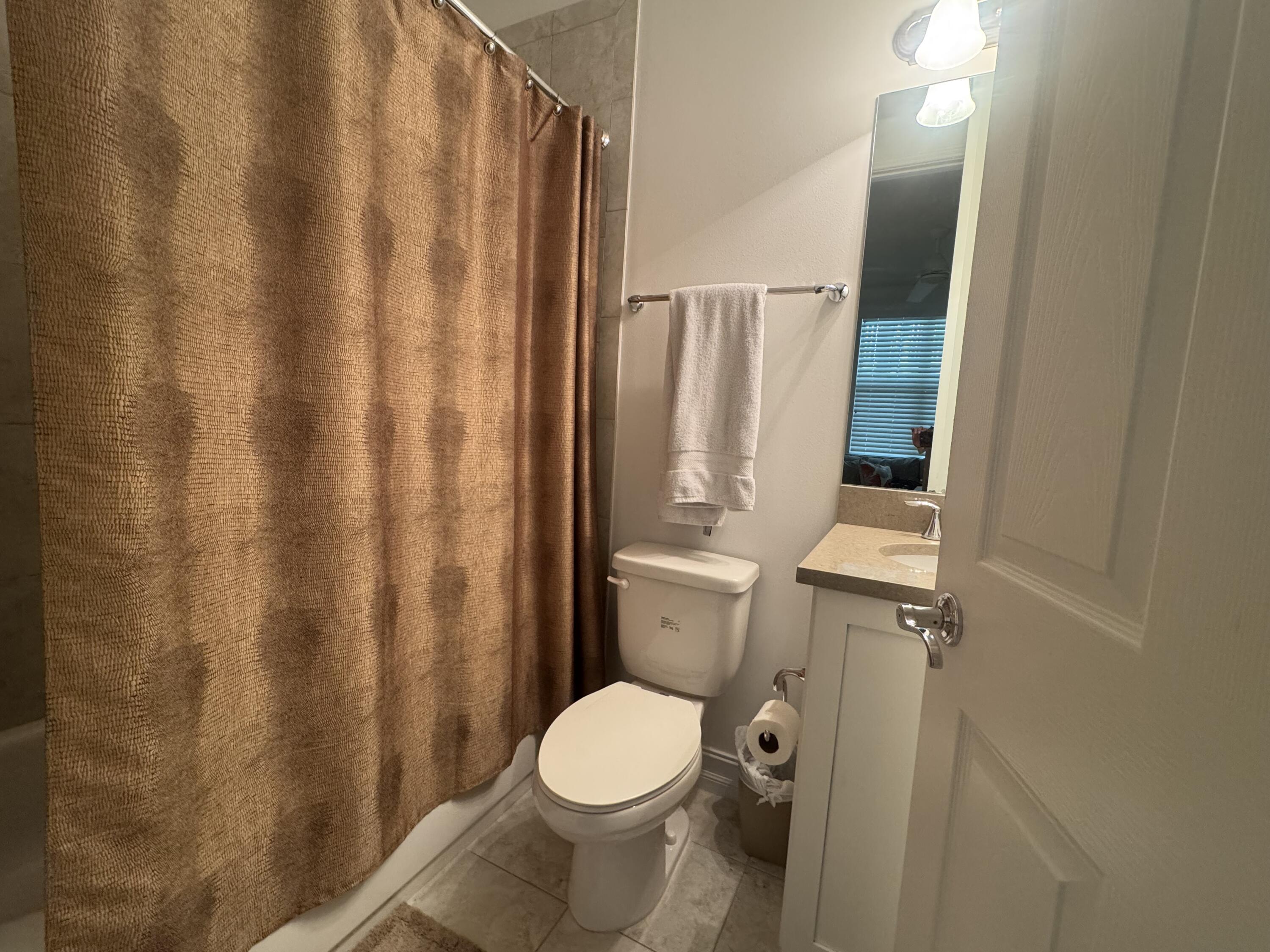 101 East Coda Circle, Unit C Delray Beach, FL 33444 - Photo 6 of 13 a white toilet sitting next to a shower curtain