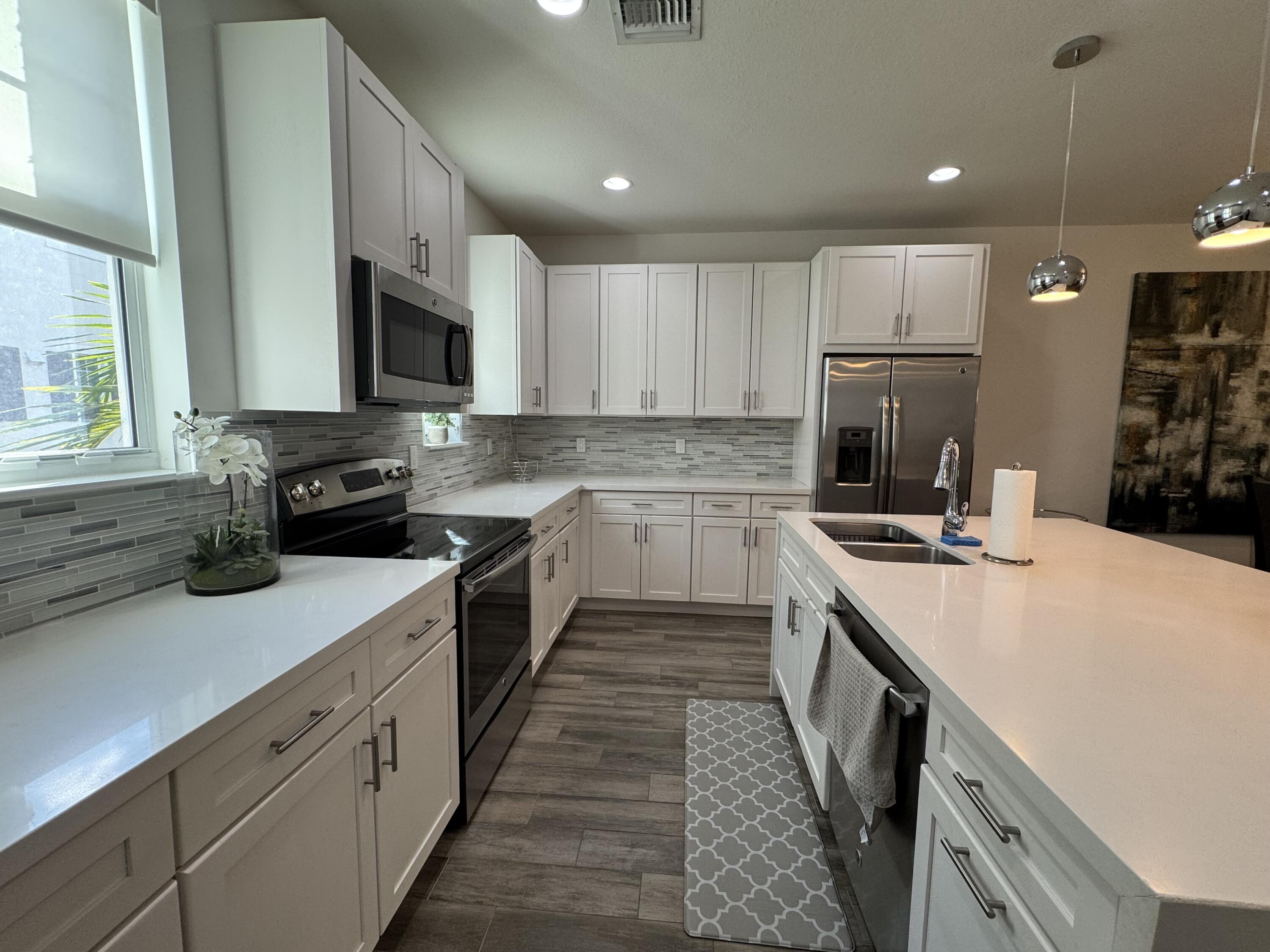 101 East Coda Circle, Unit C Delray Beach, FL 33444 - Photo 8 of 13 a kitchen with a sink a stove top oven and refrigerator