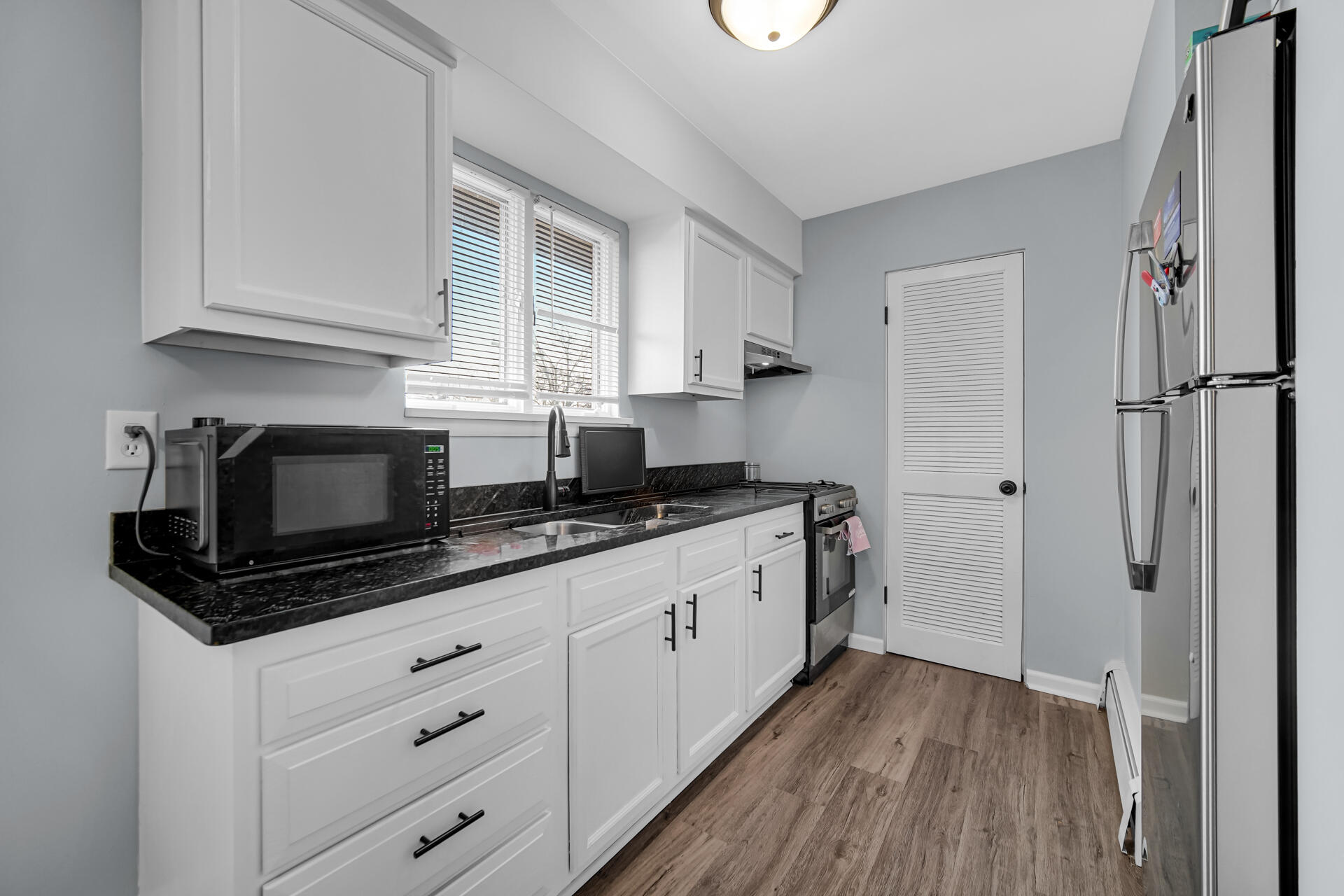 1104 169th Street Hammond, IN 46324 - Photo 10 of 20 a kitchen with granite countertop white cabinets stainless steel appliances a sink and wooden floor