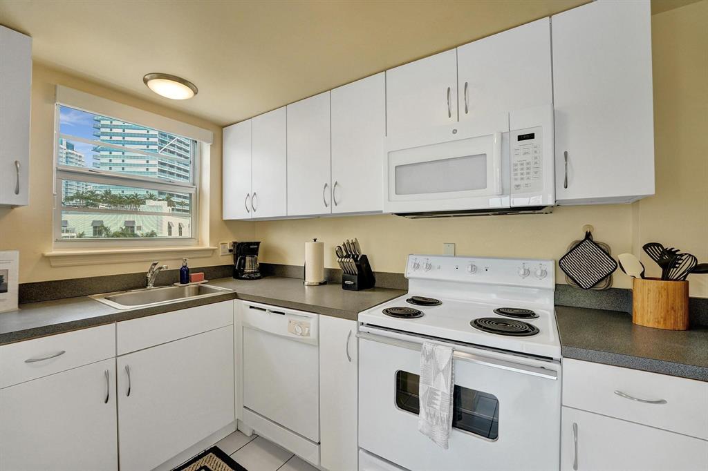 341 North Birch Road, Unit 416 Fort Lauderdale, FL 33304 - Photo 16 of 49 a kitchen with granite countertop white cabinets and white appliances