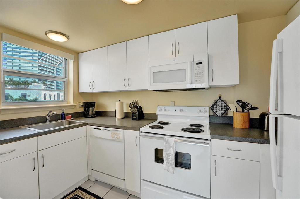 341 North Birch Road, Unit 416 Fort Lauderdale, FL 33304 - Photo 35 of 49 a kitchen with white cabinets and white appliances