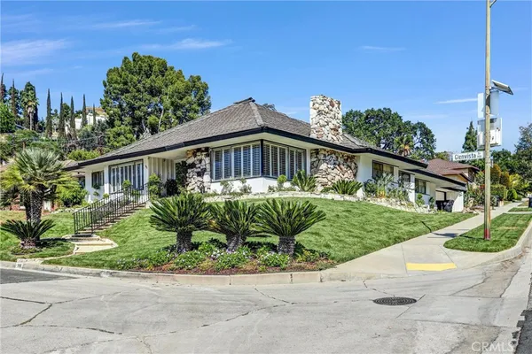 a front view of a house with a yard and potted plants